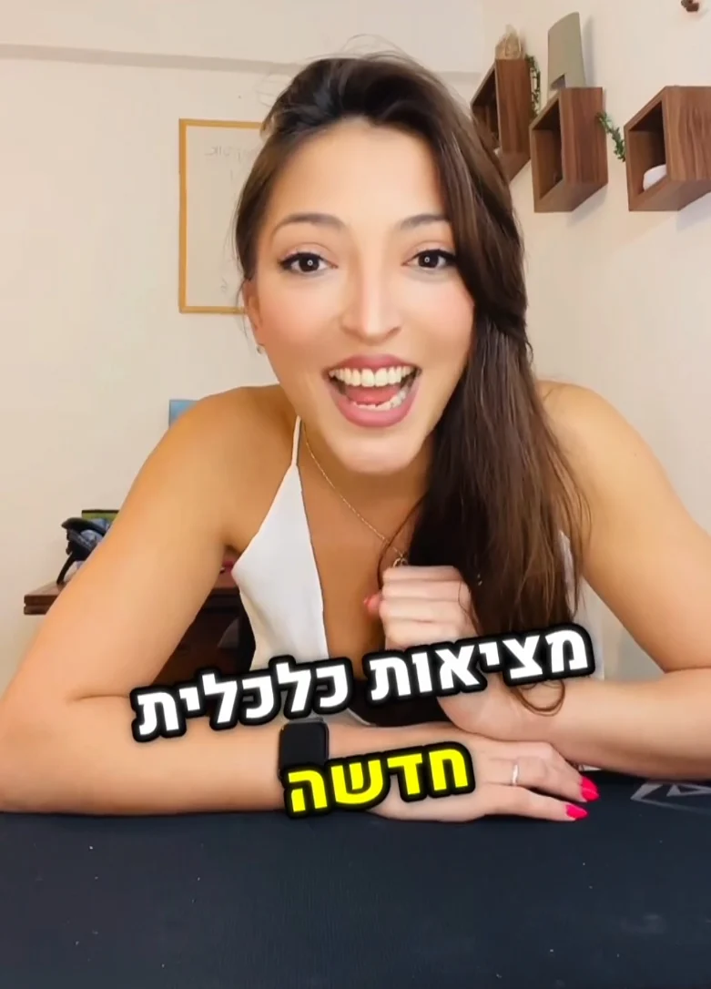 בל קסטרו מחייכת עם טקסט "מציאות כלכלית חדשה" ברקע, יושבת ליד שולחן.