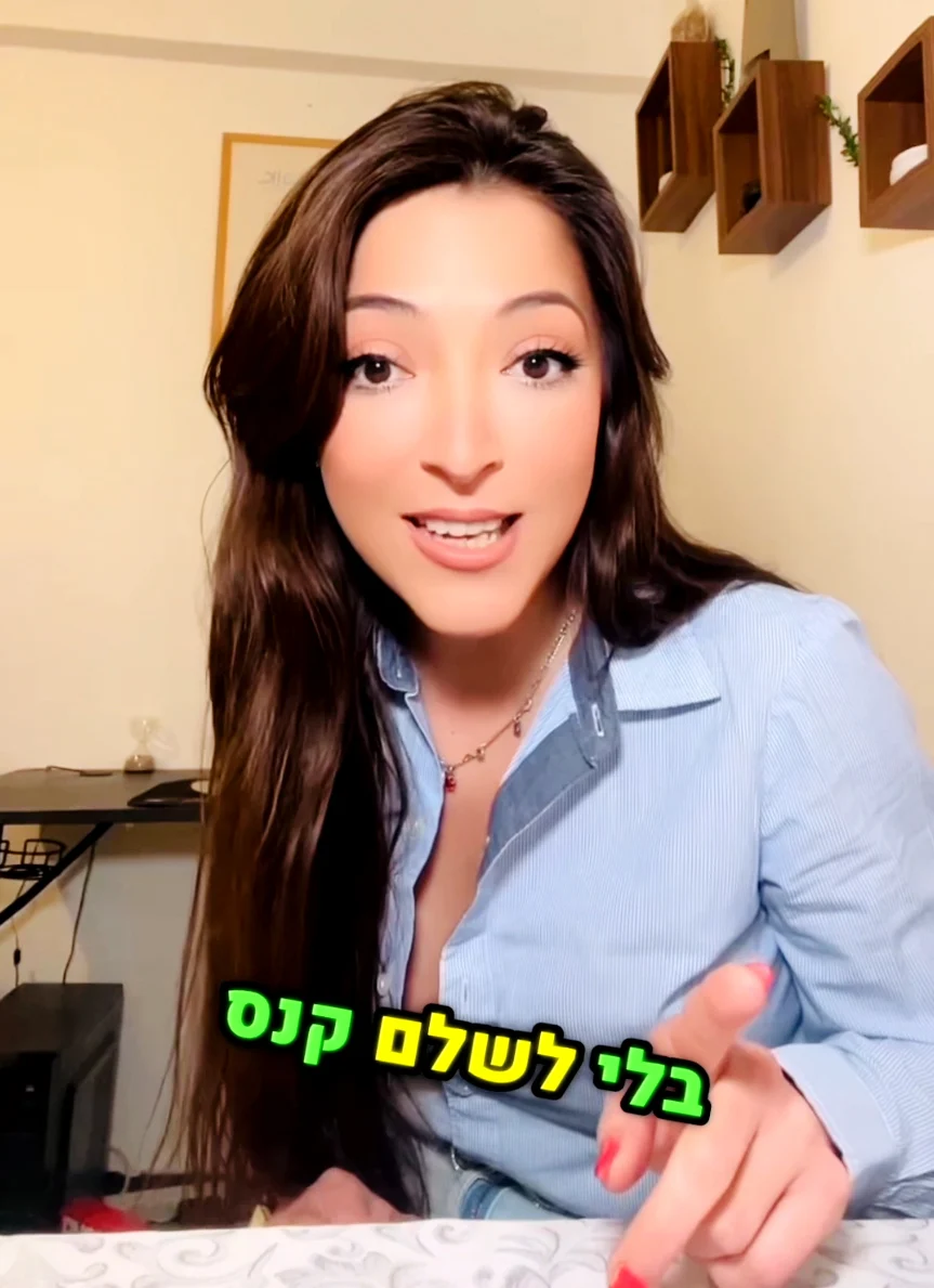 בל מדברת למצלמה, לבושה בחולצה כחולה, עם טקסט צבעוני על המסך.